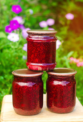banks with fragrant homemade raspberry jam in the garden. summer harvest. sweet food. food stock for the winter. countryside, outdoor. nature