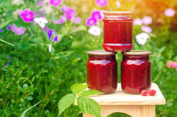 banks with fragrant homemade raspberry jam in the garden. summer harvest. sweet food. food stock for the winter. countryside, outdoor. nature