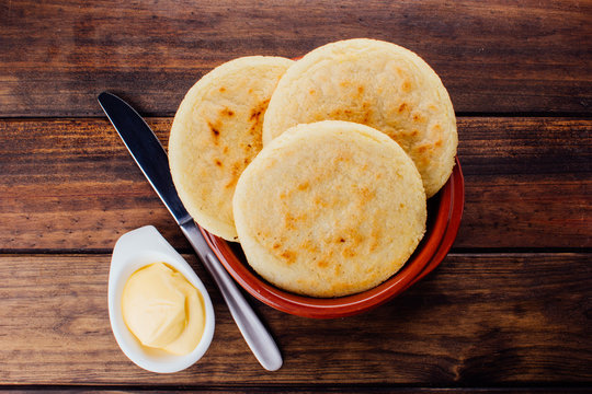 Plate with arepas and butter aside on a rustic wooden background