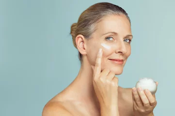 Fotobehang Mature woman applying skin cream on face © Rido