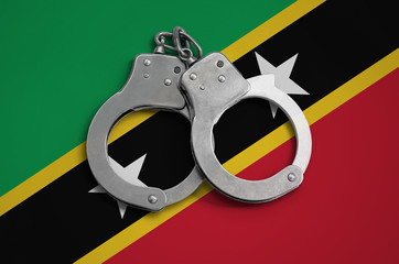 Saint Kitts and Nevis flag  and police handcuffs. The concept of observance of the law in the...
