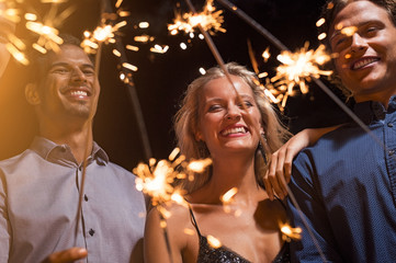 Friends holding glowing sparklers at party
