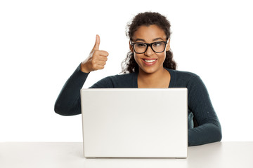 Smiling and positive happy young african-american woman with beautiful face using laptop computer, working project at desk on white background and showing thumbs up