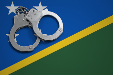 Solomon Islands flag  and police handcuffs. The concept of crime and offenses in the country