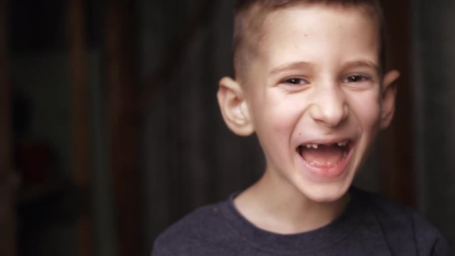 Cute boy looking at camera and laughing. Missing several front teeth. Real sincere emotions.
