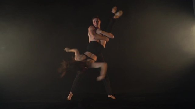 Athletic man holding a woman and turning her around in the air, slow motion