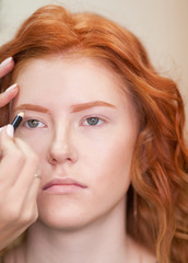 Fototapeta premium Beautiful young girl got correction of eyebrows in a beauty salon. Woman correcting eyebrows form