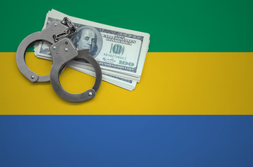 Gabon flag  with handcuffs and a bundle of dollars. The concept of breaking the law and thieves...