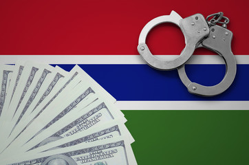 Gambia flag  with handcuffs and a bundle of dollars. The concept of illegal banking operations in...