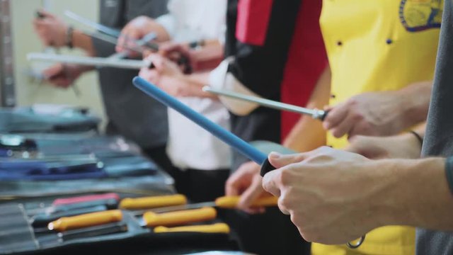 A group of chefs sharpens knifes. Cookers prepares for the master class
