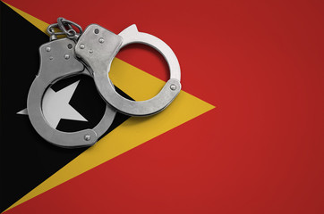 Timor Leste flag  and police handcuffs. The concept of crime and offenses in the country