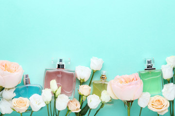 Perfume bottles with flowers on mint background