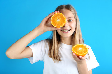 Young smiling girl with orange fruit on blue background