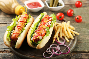 Hot dogs with vegetables and french fries on wooden table