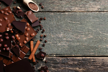 Chocolate pieces with nuts and coffee beans on wooden table