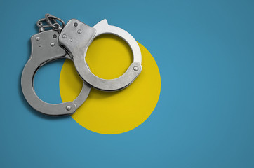 Palau flag  and police handcuffs. The concept of crime and offenses in the country
