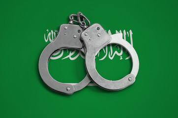 Saudi Arabia flag  and police handcuffs. The concept of observance of the law in the country and...