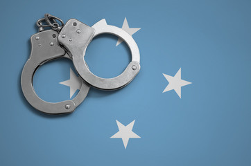 Micronesia flag  and police handcuffs. The concept of crime and offenses in the country