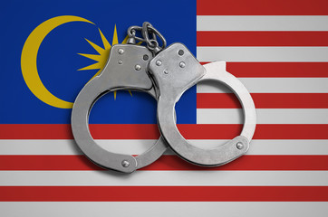 Malaysia flag  and police handcuffs. The concept of observance of the law in the country and...
