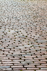 Old cobblestone street found in London. The stones are rectangular and resemble bricks. They are worn smooth from long years of use. 