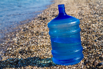 a large water bottle stands on the beach,