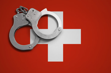 Switzerland flag  and police handcuffs. The concept of crime and offenses in the country