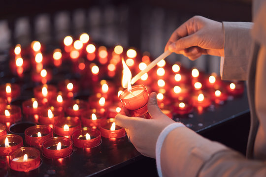 A girl is holding candle and praying near altar in church.