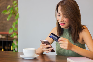 asia pretty woman are smiling face holding credit card and smartphone with coffee cup on table gray background copy space.