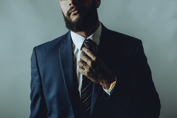 Beard man in a suit fixes tie