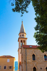 Fototapeta na wymiar Facade of old historical buildings and high church tower in central district at ancient city Budva, Montenegro