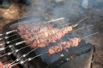Natural texture. Shish kebab on the grill on skewers in the smoke. Fry meat with onion on skewers