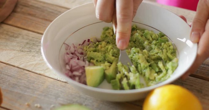 Guacamole dip sandwiches making, squeezing avocado using kitchen fork, steadicam close-up