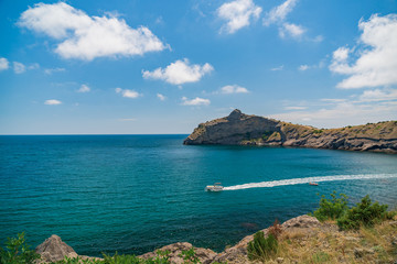 Blue sea with the rocky shore in the sunny afternoon