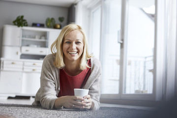 Happy woman relaxing at home, drinking coffee