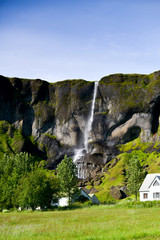An Icelandic waterfall with house beneath it