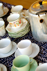 stacks of china tea cups and saucers and a metal kettle