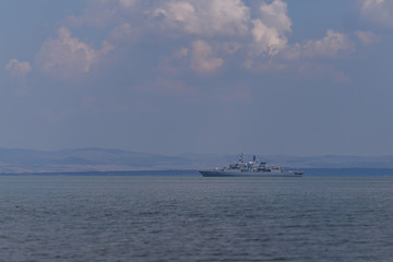 a warship floats in the water against the background of a dramatic sky. a naval vessel is taken to the port after another drilling or patrolling on water and the protection of the sea border.