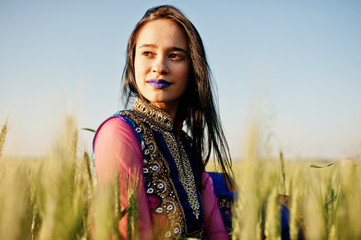 Tender indian girl in saree, with violet lips make up posed at field in sunset. Fashionable india...