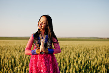 Tender indian girl in saree, with violet lips make up posed at field in sunset. Fashionable india model.