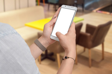 Woman's hands holding phone with empty screen, restaurant table in background. Mockup