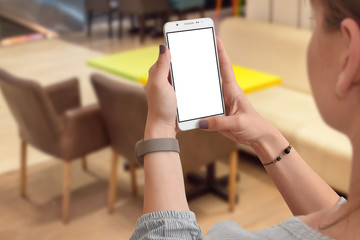 Woman's hands holding smartphone with empty screen, blurred cafe in background