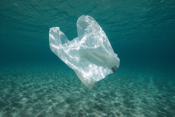 Plastic waste underwater, a plastic bag in the Mediterranean sea between water surface and a sandy...