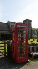 Typical English Red Telephone booth in front of an old church in Snowshill England