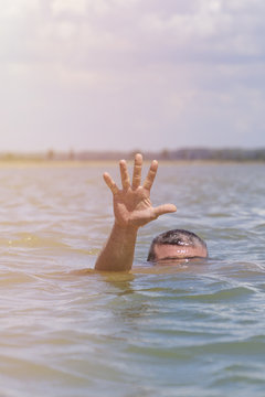  right man's hand gives a signal for help out of the water
