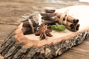 Pieces of chocolate, cinnamon, mint and star anise on the serving Board.