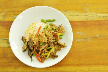 spicy fried duck meat curry with basil leaf and rice on plate