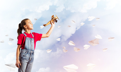 Concept of careless happy childhood with girl throwing retro plane