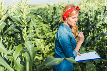 beautiful farmer checking harvest with clipboard in field at farm
