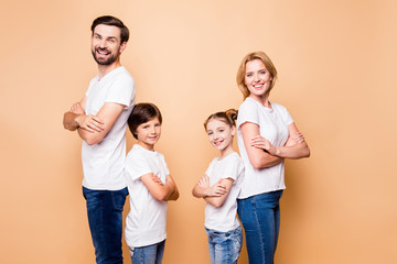 Portrait of adorable attractive happy smiling confident family, bearded father, blonde mother spouses standing back to back with their little children wearing jeans and white T-shirts, folded hands