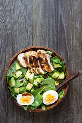 Green lunch bowl with grilled chicken, avocado and eggs. Healthy and dietary food. Space for text.